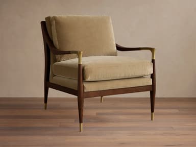 A plush armchair with a wooden frame and velvet upholstery. The armchair features a high back and seat cushions, with elegantly curved wooden arms. Decorative brass accents are present on the armrests and the tapered legs, which are capped with brass. — 3D model