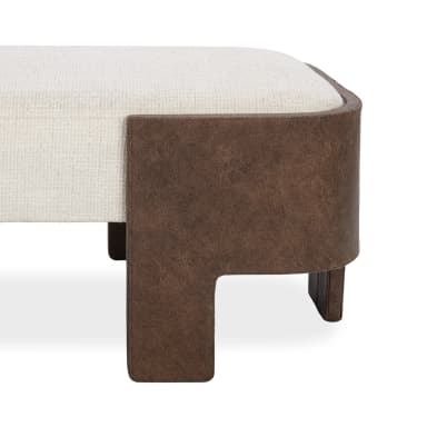 A close-up view of a modern upholstered bench, featuring a rectangular, cushioned top covered in a light, textured cream fabric. The base and integrated legs are constructed from a rich, distressed brown leather or faux leather material, designed with a distinct L-shaped structure at the corners that provides sturdy support and a contemporary aesthetic. — 3D model