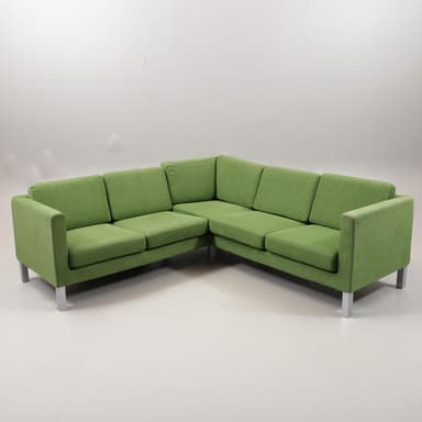 A modern L-shaped sectional sofa upholstered in a textured green fabric, featuring distinct seat and back cushions, track arms, and exposed square-profile silver-toned metal legs. The sofa is composed of two interconnected sections forming a right-angle configuration. — 3D model