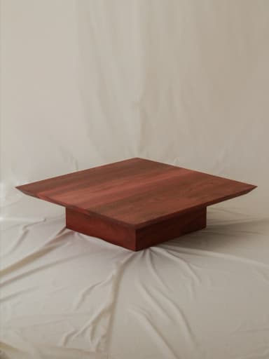 A modern, square-shaped coffee table crafted from reddish-brown wood, featuring a thick tabletop that appears to float above a substantial, square pedestal base. — 3D model