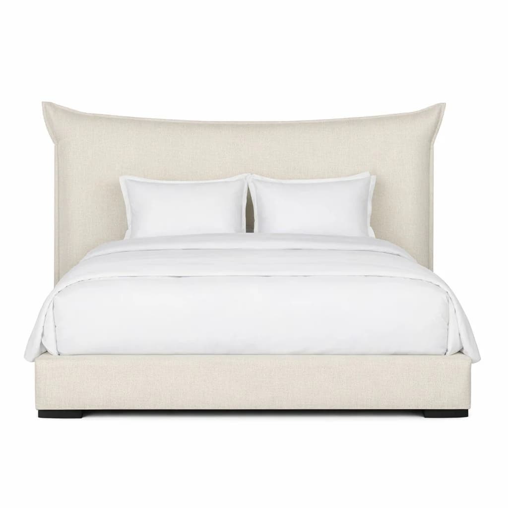 A fully upholstered bed frame with a tall, winged headboard. The headboard features a gentle curve at the top and flares outwards towards the sides, creating a wingback silhouette. The bed frame is also upholstered, with clean lines and a low profile. Two white pillows and white bedding are present on the mattress. — 3D model
