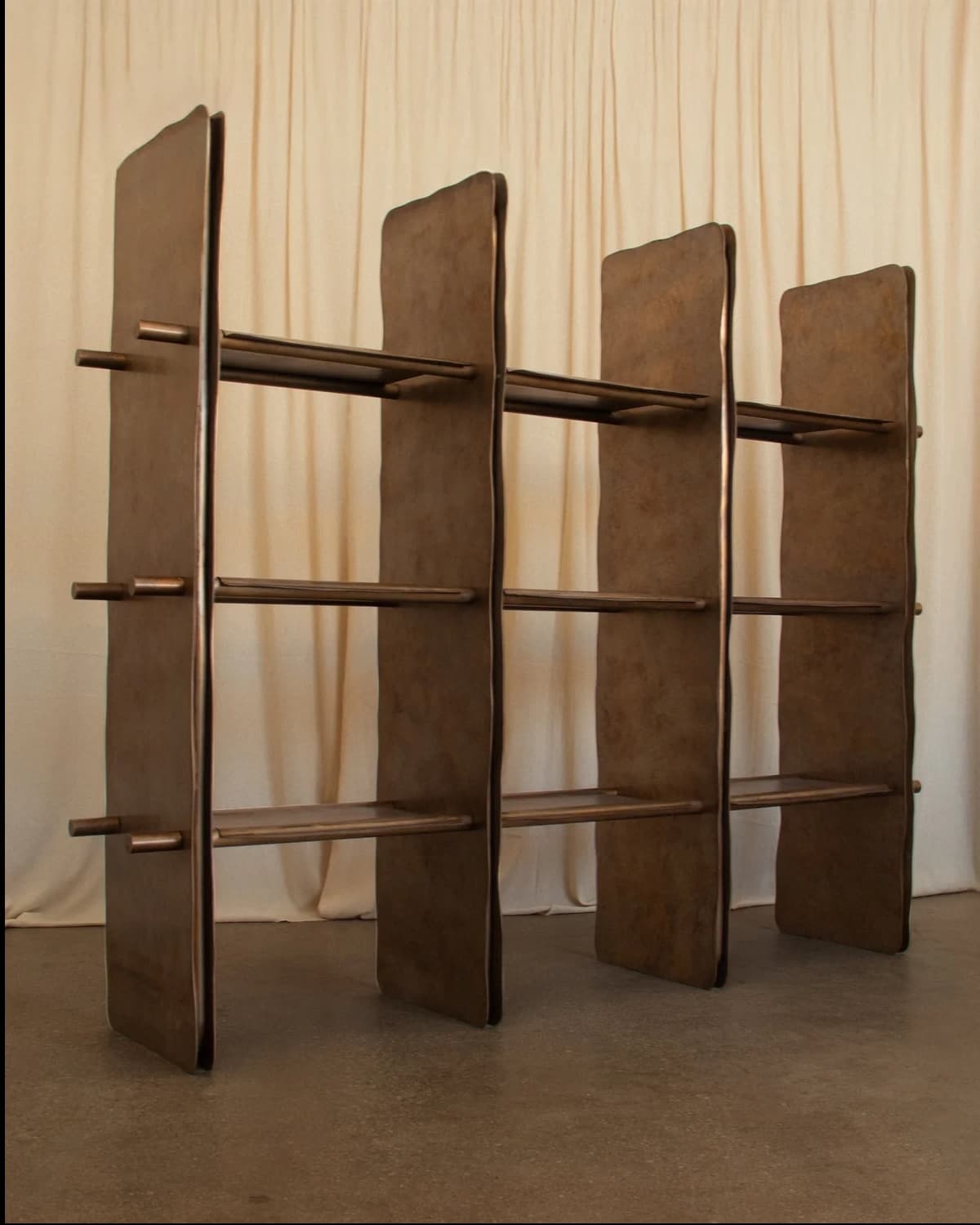 A brown, modular open-back shelving unit featuring three vertical partitions and three horizontal shelves, creating a grid of nine compartments. All components have subtly rounded edges. Small cylindrical pegs protrude from the exterior of the outermost vertical side panels. — 3D model