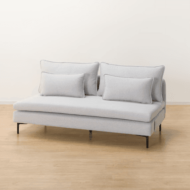 A contemporary armless chaise loveseat, upholstered in a light gray textured fabric. It features a low-profile design with a deep, elongated seat on the right side, resembling a chaise. The seating is supported by minimalist black metal legs, and the piece includes two large back cushions and two smaller rectangular throw pillows, all with subtle piped edges. — 3D model
