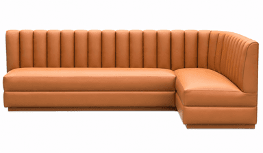 A corner booth-style seating unit with a fluted backrest and upholstered cushions. The unit is L-shaped, designed to accommodate multiple individuals. The upholstery features a consistent sheen, suggesting a synthetic leather or vinyl material. The design incorporates vertical channeling on the backrest and smooth surfaces on the seat and arms. — 3D model