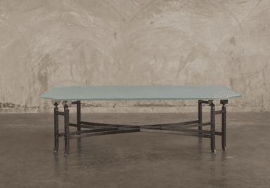 A low-profile table featuring a frosted glass top with an octagonal shape, supported by a wrought iron base with intricate curved and intersecting elements. Decorative brass finials connect the glass top to the metal base. — 3D model