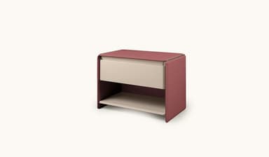 A contemporary nightstand with a single drawer and an open shelf below. The exterior casing and top surface appear to be upholstered in a light brown or beige material, possibly leather or a textured fabric, with visible stitching along the edges. The drawer front is a contrasting white, and the open shelf is also white, creating a two-tone aesthetic. The design features rounded corners and a minimalist silhouette. — 3D model