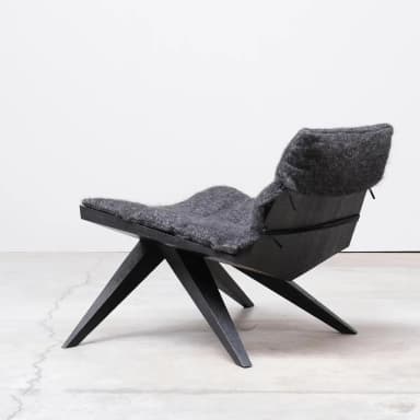 A low-profile, modern lounge chair featuring a dark, angular wooden frame and a thick, soft grey felted wool cushion. — 3D model