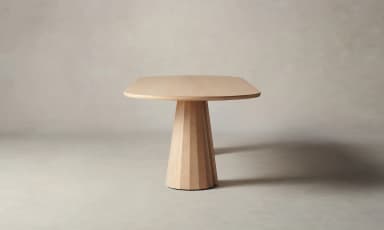 An oval-shaped dining table with a light wood finish. The tabletop is relatively thin with rounded edges. It is supported by two conical bases, each featuring a fluted or segmented design, tapering from a wider base to a narrower top where they connect to the underside of the tabletop. The bases appear to be made of solid wood. — 3D model