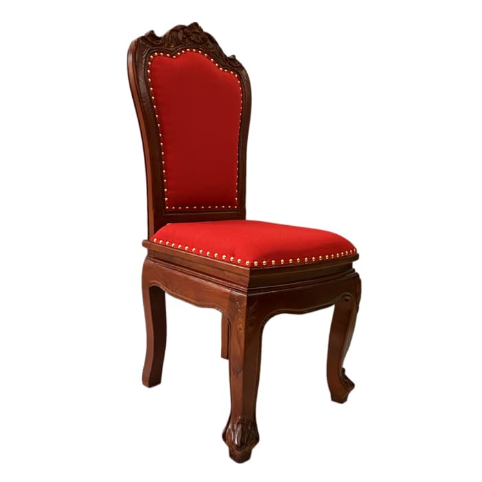 An ornate side chair featuring a dark-stained carved wooden frame and rich red upholstery. The chair's backrest has a high, decorative crest rail with intricate floral and scroll carvings, characteristic of Baroque or Rococo styles. Both the seat and the back are upholstered in a textured red fabric, outlined with a continuous line of brass or gold-toned nailhead trim. The chair stands on gracefully curved cabriole legs, terminating in carved feet, and the front apron also exhibits subtle carving. — 3D model