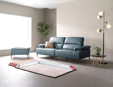 A modern sectional sofa featuring a right-hand facing chaise lounge, upholstered in a blue leather-like material. It has plush, segmented seat and back cushions, gently padded rolled armrests, and is supported by slim, tapered dark metal legs. An accent pillow with a geometric pattern is included. — 3D model