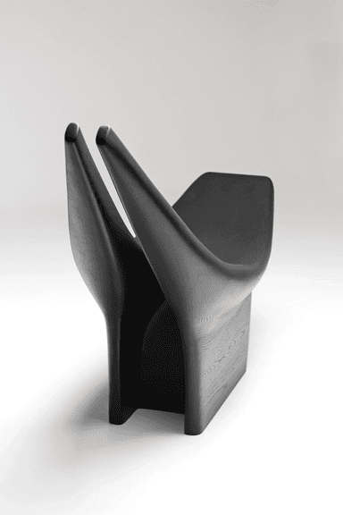 A striking, sculptural lounge chair crafted from a dark, apparently solid material, featuring a deeply reclined seat that integrates into a distinctive split backrest resembling two upward-curving horns. The chair rests on a solid, rectilinear base, and its surface exhibits subtle striations, suggesting a milled or sculpted construction. — 3D model
