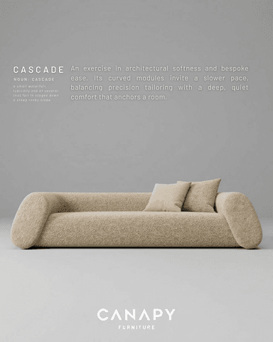 A long, low-profile sofa with rounded edges, upholstered in a light beige, textured fabric, accompanied by two matching throw pillows. Its design features integrated, gently curved armrests and backrest, creating a continuous, minimalist form that extends to the floor. — 3D model