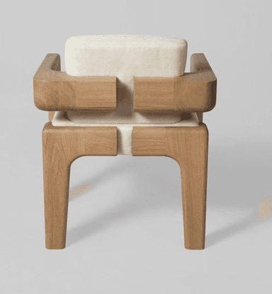 An armchair with a distinct contemporary design. The frame is constructed from light-colored wood with a visible grain, featuring robust legs and armrests. The seat and backrest are upholstered in a textured, off-white fabric that appears soft and plush. The design incorporates geometric shapes, with the wooden elements forming block-like structures that cradle the upholstered cushions. — 3D model