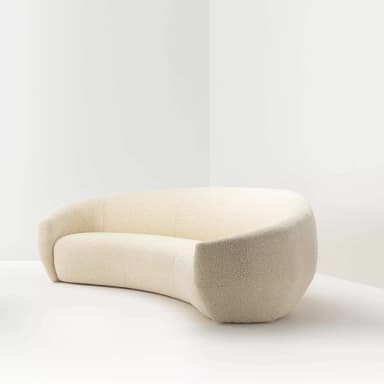 A cream-colored, curved sofa with a textured fabric upholstery. The sofa features a continuous, organic form with no visible legs, appearing to rest directly on the floor. Its design is modern and sculptural, with a rounded back and seat that create a sense of enclosure. — 3D model