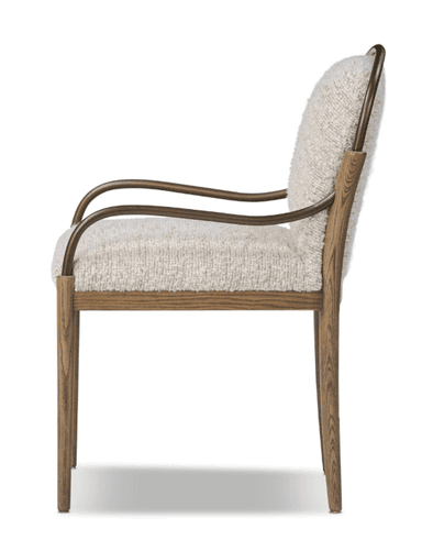 An armchair with a upholstered seat and back, featuring a textured cream-colored fabric. The frame consists of wooden legs and a wooden horizontal support, complemented by curved metal armrests with a bronze finish. The design blends natural and metallic elements. — 3D model