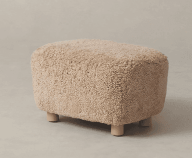 A rectangular ottoman or footrest upholstered in a light beige, fluffy, boucle-textured fabric, supported by four short, light-colored wooden cylindrical legs. — 3D model