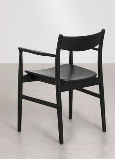 A modern black-stained wooden armchair with a minimalist design, featuring a gently curved backrest, integrated armrests, and a solid wood seat. The chair's legs are slightly tapered, contributing to its sleek aesthetic. — 3D model