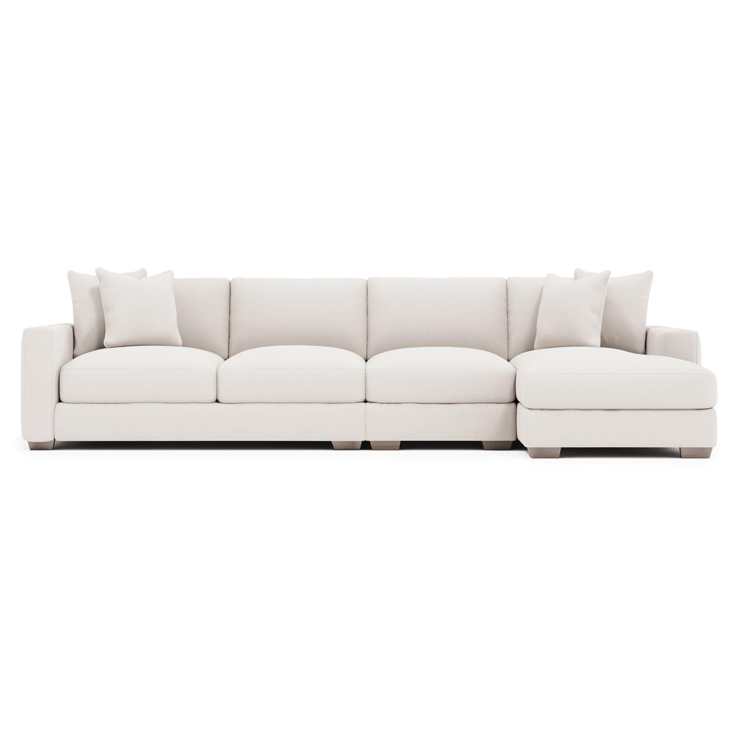 A contemporary sectional sofa, upholstered in a light-colored, textured fabric. It features a chaise lounge on the right side and comes with multiple throw pillows. The sofa has clean lines, plush cushions, and low-profile wooden legs. — 3D model