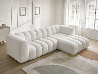 A white, modular sectional sofa with a chaise lounge extension. The sofa features a distinctive channel-tufted design on its seat cushions, backrests, and chaise. The upholstery appears to be a textured boucle fabric. The sofa has a low profile with concealed legs, giving it a contemporary aesthetic. — 3D model