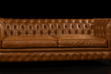 A classic Chesterfield sofa upholstered in rich brown leather, featuring distinctive button tufting on the backrest, rolled arms, and front apron. It has two separate seat cushions and stands on short, turned wooden feet. — 3D model