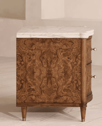A two-drawer nightstand with a marble top. The main body of the nightstand is constructed from wood with a distinctive burl veneer on the drawer fronts. The drawer fronts are curved and feature two rectangular pulls with white inserts and brass accents. The nightstand is supported by four tapered legs, also with brass ferrules at the base. — 3D model
