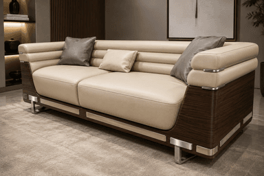 A contemporary two-seater sofa featuring cream-colored leather upholstery, dark wood paneling, and polished metal accents. The design incorporates clean lines with horizontal channel tufting on the backrest and armrests. It includes two loose seat cushions and comes with three accent throw pillows in varying shades of grey and cream. The sofa is supported by low-profile metal feet, and the wood paneling wraps around the base and arms. — 3D model