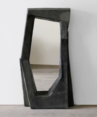 A freestanding mirror with an irregularly shaped frame. The frame has a rough, textured surface and an abstract, angular design. The mirror itself is rectangular with chamfered edges and is centrally positioned within the frame. — 3D model