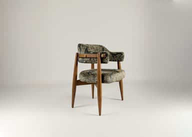 A wooden accent chair with two upholstered seating surfaces. The frame is constructed from light brown wood with tapered legs. The upholstery is a dark fabric with an intricate, possibly embroidered, pattern in a lighter color, featuring scrollwork and geometric motifs. A brass-colored latch or buckle detail is visible on the upper upholstered section. — 3D model