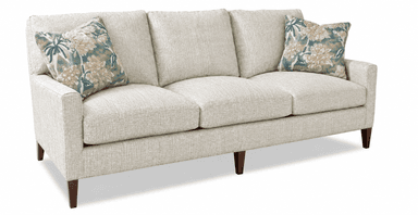 A contemporary three-seater sofa upholstered in a light, textured fabric, featuring clean lines and track arms. It includes three removable seat cushions and three removable back cushions, accompanied by two floral-patterned throw pillows. The sofa is supported by dark, tapered wooden legs. — 3D model