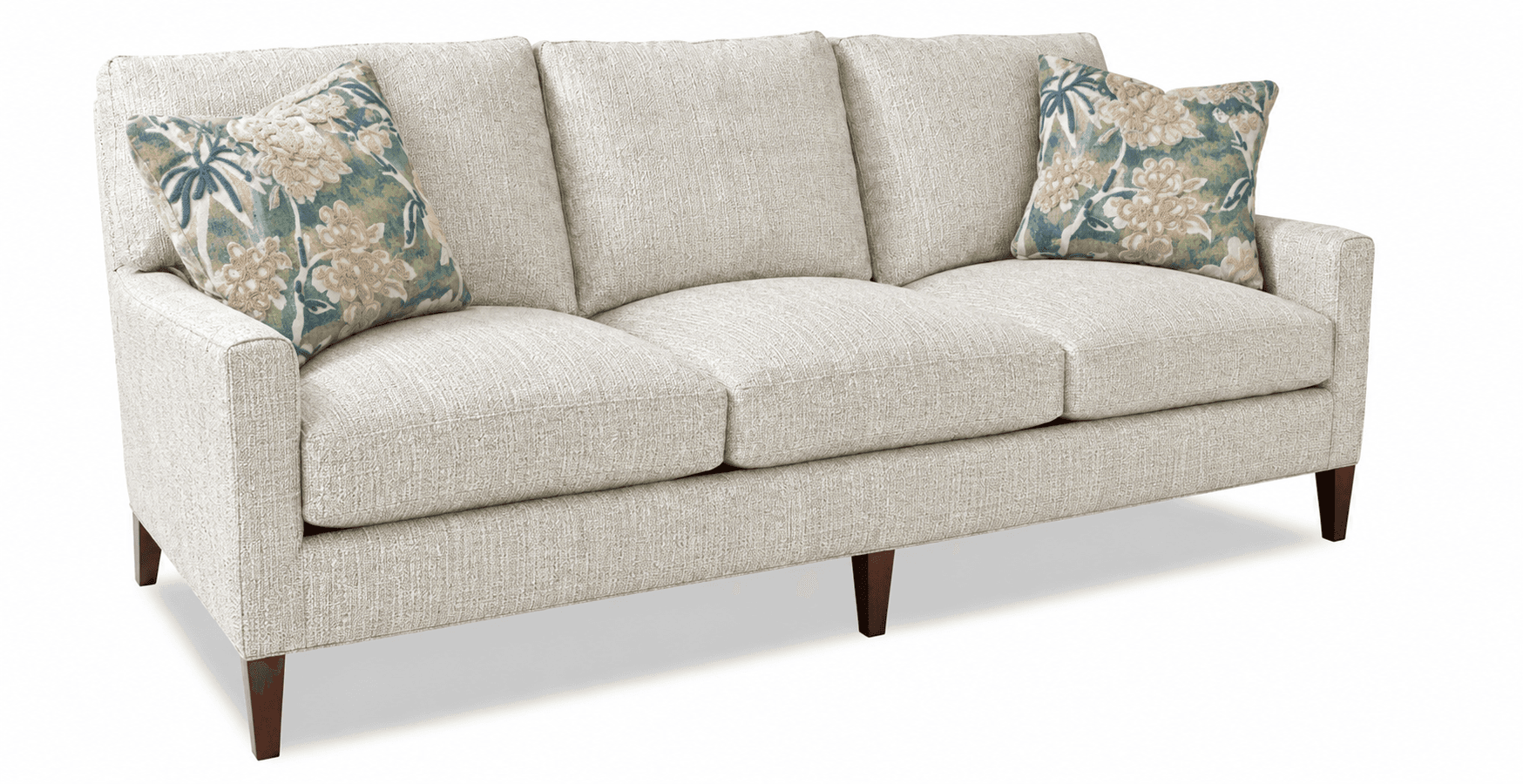 A contemporary three-seater sofa upholstered in a light, textured fabric, featuring clean lines and track arms. It includes three removable seat cushions and three removable back cushions, accompanied by two floral-patterned throw pillows. The sofa is supported by dark, tapered wooden legs. — 3D model