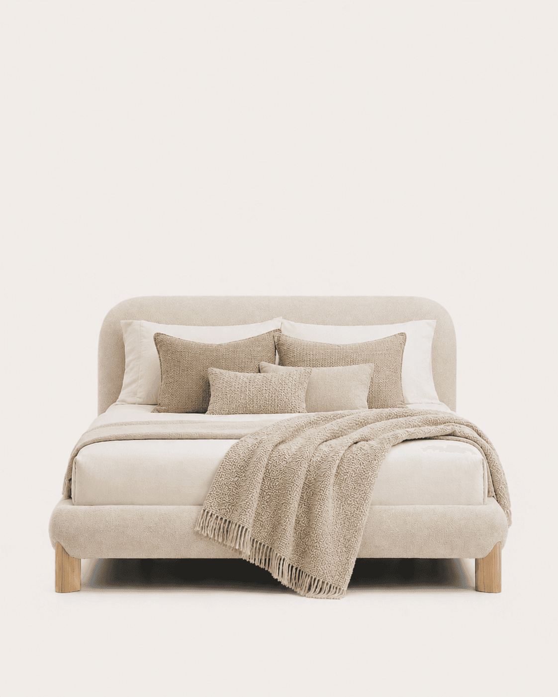A contemporary platform bed featuring a fully upholstered frame and a gently rounded headboard. The bed is covered in a textured, light beige fabric, providing a soft and inviting aesthetic. It stands on short, cylindrical wooden legs, slightly recessed, giving the impression of a floating base. The bed is dressed with white sheets, several textured throw pillows in varying shades of beige and cream, and a chunky knit throw blanket draped over the foot. — 3D model