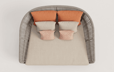 A contemporary daybed constructed with a woven rope frame and a metal base. It features a plush, light-colored cushion and several decorative pillows in coral and beige tones. The design suggests suitability for outdoor or modern indoor use. — 3D model