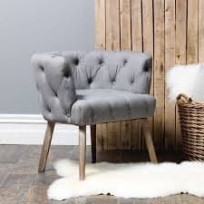 A tufted armchair with a curved back and integrated arms, supported by four tapered wooden legs. The upholstery features diamond-pattern button tufting across the seat, back, and armrests. — 3D model