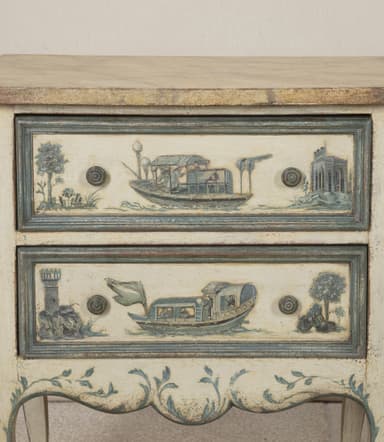 A pair of matching nightstands with two drawers each. The front panels of the drawers and the lower skirt are adorned with hand-painted blue and white scenic details, featuring boats and architectural elements. The nightstands have a distressed cream-colored finish and are supported by four cabriole legs. The top surface appears to be a different material, possibly a veneer or stone. — 3D model