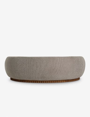 A curved sofa with a rounded silhouette, featuring a textured fabric upholstery and a distinctive wooden base with vertical fluting. The sofa has integrated armrests that flow into the backrest, creating a continuous, organic form. The base is composed of numerous closely spaced, vertical wooden elements. — 3D model
