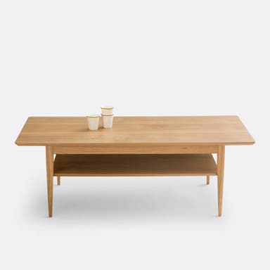 A rectangular coffee table constructed from natural oak wood, featuring a spacious tabletop and a functional lower shelf. It is supported by four elegantly tapered, round legs. — 3D model