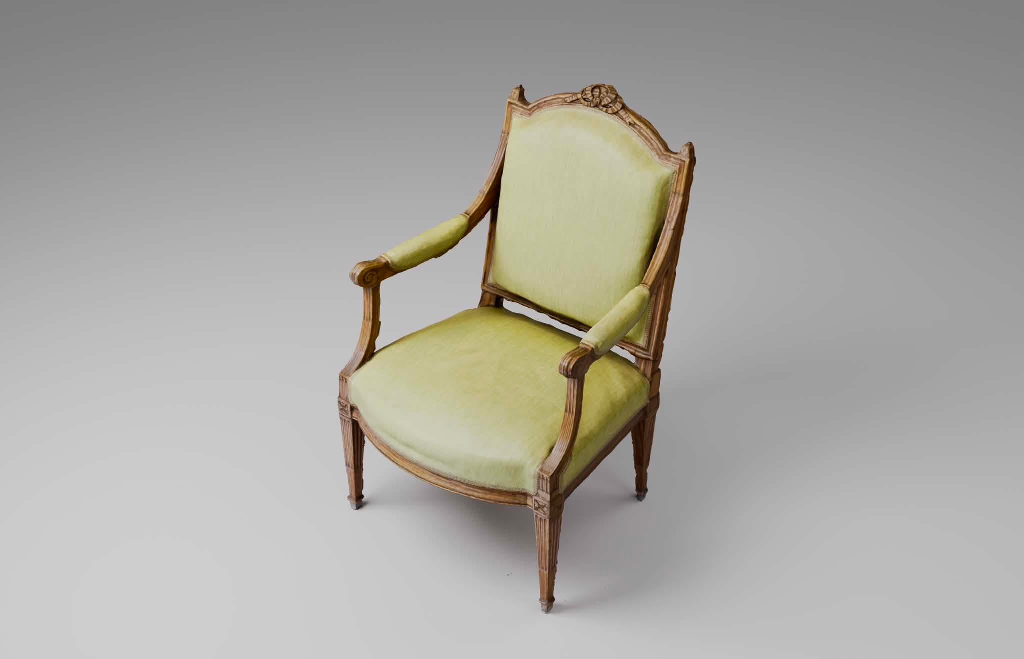An antique or reproduction armchair featuring a carved wooden frame and upholstered seat, backrest, and arm pads. The frame displays neoclassical design elements, including fluting on the legs and arm supports, and a decorative floral carving on the crest rail. The upholstery is a light, muted green fabric. — 3D model