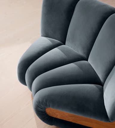 A modern, sculptural two-seater loveseat upholstered in deep blue velvet, featuring distinctive curved burl wood panel accents on its sides. — 3D model