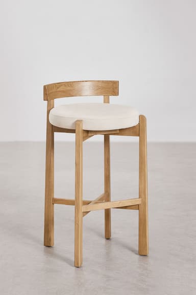 A modern bar stool featuring a light-toned oak wood frame and a circular cream upholstered seat. It has a low, gently curved backrest and a square-profile leg structure with an X-shaped cross-brace footrest. — 3D model