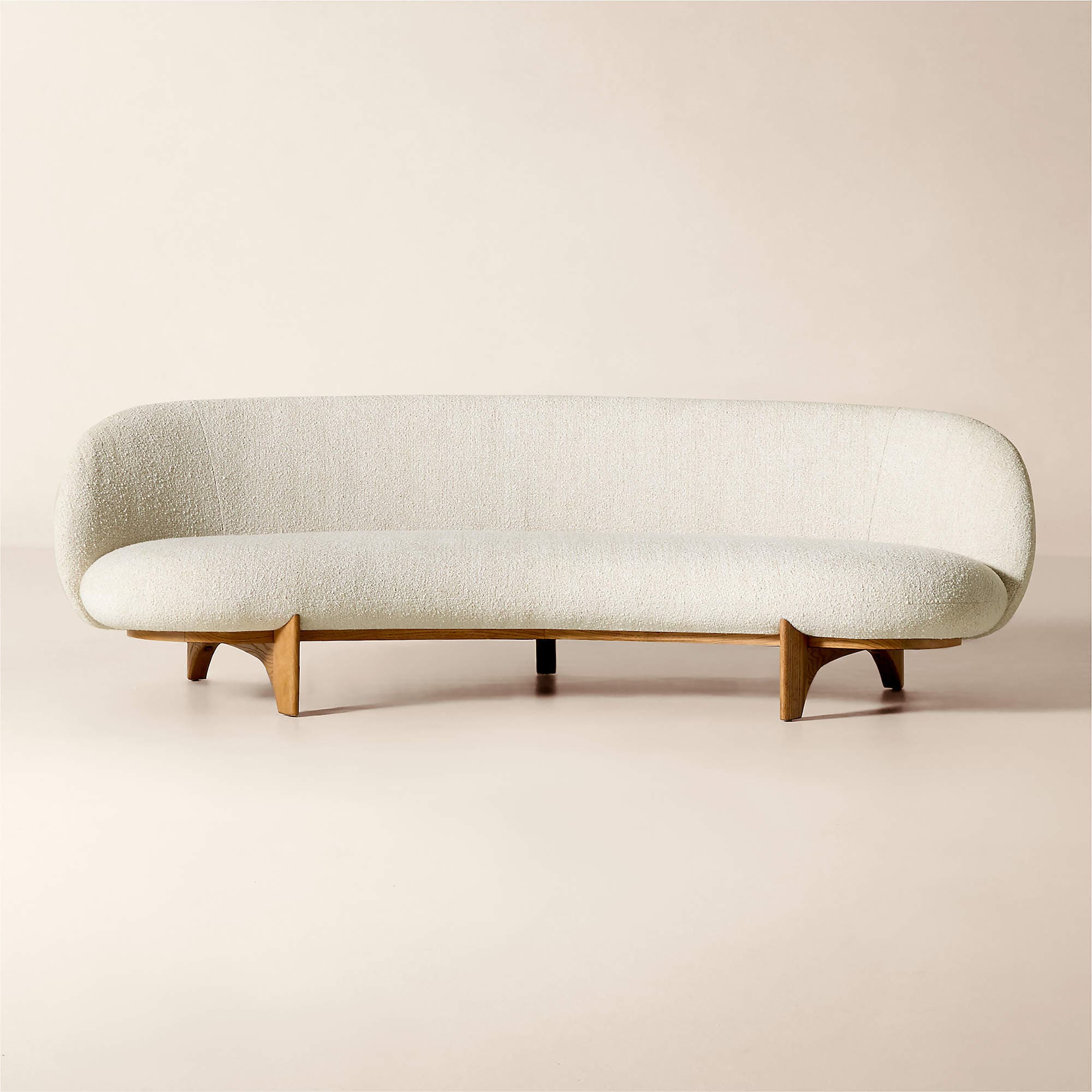 A mid-century modern inspired sofa with a curved back and seat, upholstered in a textured cream fabric. It is supported by a low-profile wooden base with distinctive V-shaped legs. — 3D model