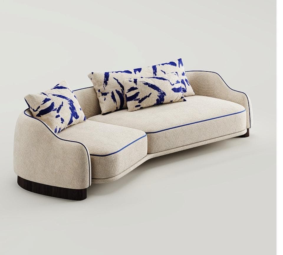 A modern curved sectional sofa featuring a textured cream-colored upholstery with distinct blue piping along the edges of the cushions and frame. The sofa has a low-profile, sleek design with rounded armrests and a dark wood plinth base. It is composed of two main sections forming an L-shape, accompanied by several throw pillows with a blue abstract brushstroke pattern. — 3D model
