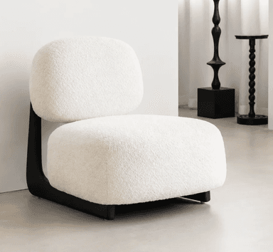 An armless, low-profile lounge chair featuring soft, rounded forms and upholstered in a textured off-white bouclé fabric. The seating and backrest cushions appear plush and inviting, supported by a distinctively shaped black base that provides a modern, minimalist foundation for the chair. — 3D model