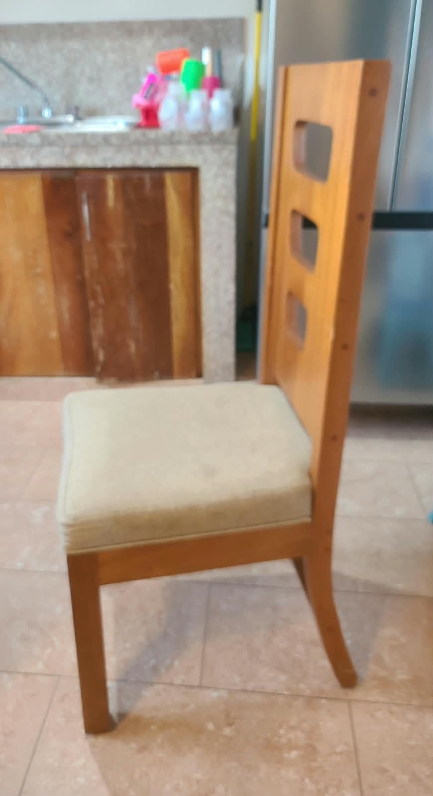 A modern dining chair constructed from light-toned wood, featuring an upholstered seat and a distinctive backrest with horizontal slats. The chair has a minimalist design with straight front legs and gently curved rear legs, providing stability and support. — 3D model