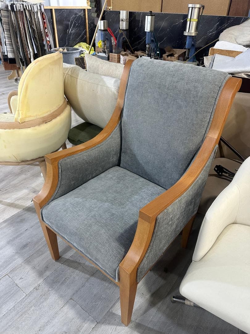 An upholstered armchair featuring a prominent light-colored wooden frame and gray fabric upholstery on the seat, back, and side panels. The chair has a high back and visible wooden armrests that curve downwards towards the front legs. — 3D model