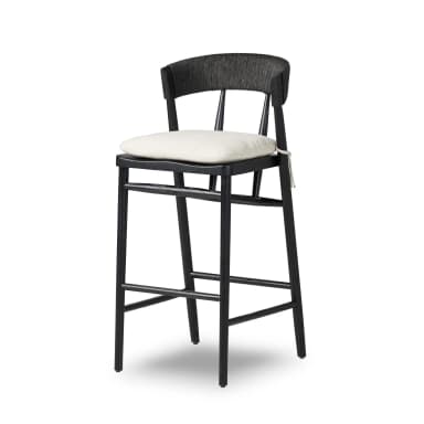 A modern bar stool with a black wooden frame and a woven backrest. It features a lightly upholstered, square seat cushion in a neutral tone. The stool has four legs connected by crossbars for stability. A white string is tied to one of the front legs. — 3D model