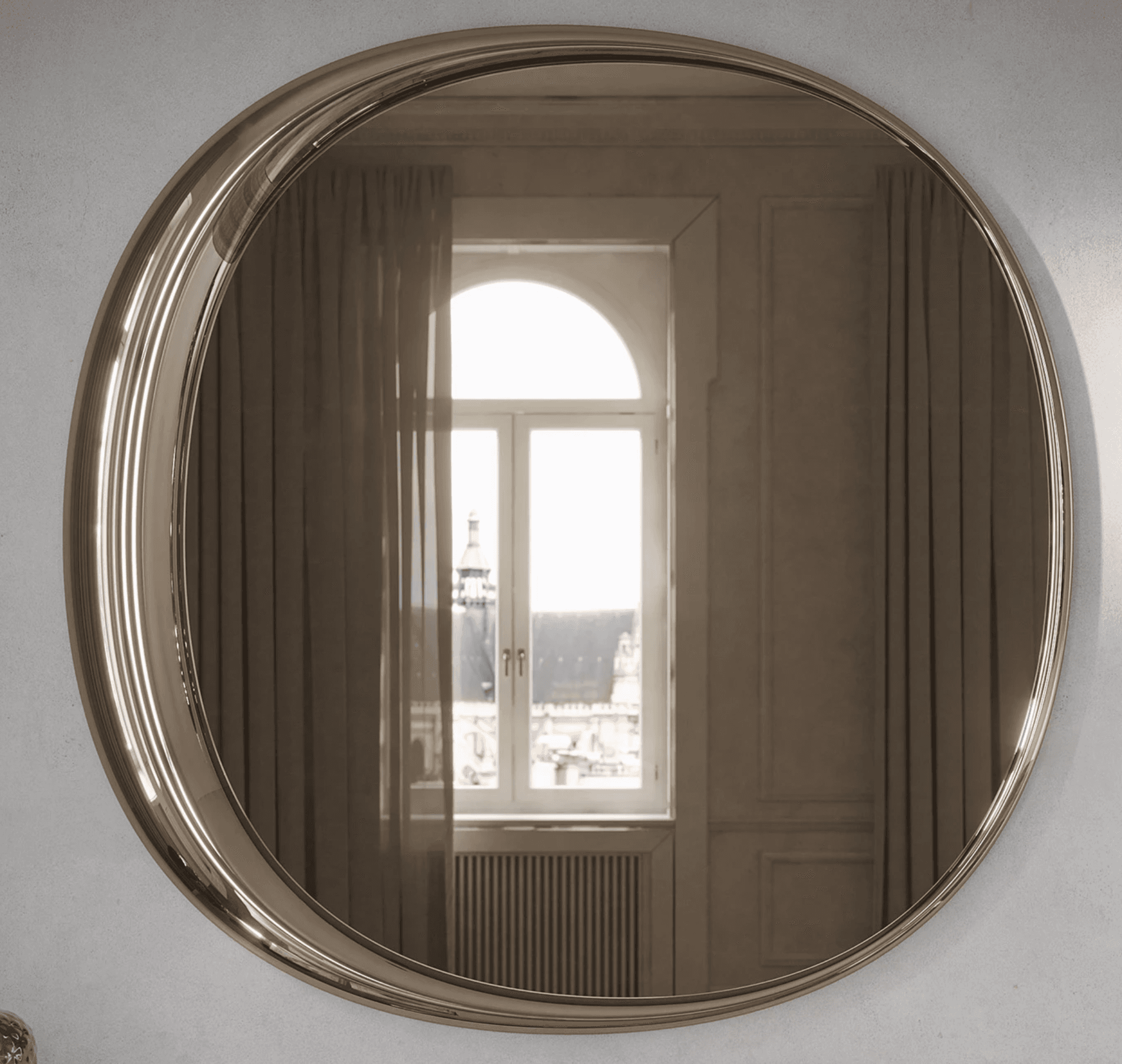 A large, round wall-mounted mirror featuring a wide, polished metallic frame. The frame has distinct fluted or reeded detailing that adds texture and depth. The mirror glass itself appears to have a slight smoky or bronze tint, reflecting a bright window view. The overall aesthetic suggests a luxurious and decorative piece. — 3D model
