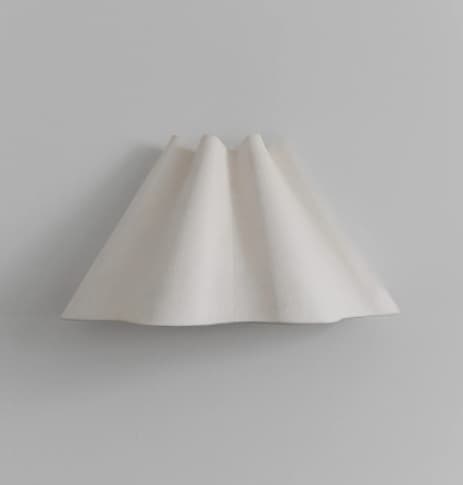 A contemporary pendant light featuring a folded or pleated shade. The shade appears to be made of a translucent material, possibly glass or resin, with a matte white finish. The pleats create a dynamic, organic form that diffuses light softly. The base, where the shade attaches to the suspension system, is not visible in this image, but the overall design suggests a modern, minimalist aesthetic. — 3D model