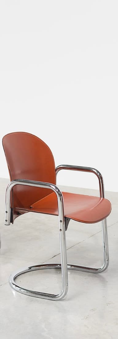A cantilever armchair with a chrome-plated tubular steel frame and a brown leather seat and backrest. The frame has a continuous curve forming the legs, seat support, and armrests. The backrest is slightly curved and extends upwards, with a visible seam running along its edge. The seat is a flat plane that connects to the frame. The overall design suggests a mid-century modern or Bauhaus influence. — 3D model