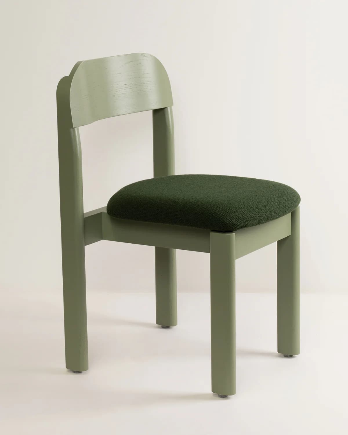 A modern dining chair featuring a sage green wooden frame with cylindrical legs and a gently curved backrest, paired with a dark green upholstered round seat. — 3D model