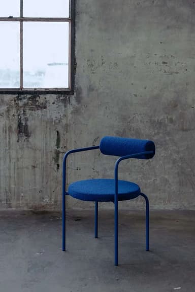 A contemporary accent chair with a circular seat and a cylindrical backrest, supported by a slender metal frame. The upholstery is a textured, deep blue fabric. — 3D model